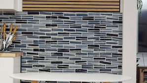 A kitchen with a white countertop, a tiled backsplash, and a wooden slatted panel above the counter. - Coast PalmTree Yard 2BR Block from Beach (Pacifica)