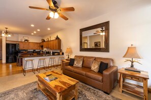 A modern living room with a brown leather sofa, a wooden coffee table, and a ceiling fan. - Experience comfort and adventure at Peregrine Point 103, a spacious 2-bedroom condo (Durango)