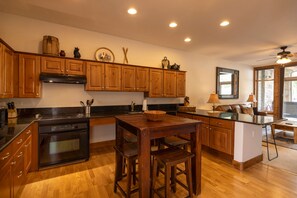 A kitchen with wooden cabinets, a built-in oven, a dining table with chairs, and a large window providing natural light. - Experience comfort and adventure at Peregrine Point 103, a spacious 2-bedroom condo (Durango)