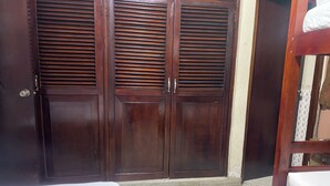 Una habitación con un armario de madera, una cama y una silla de madera.