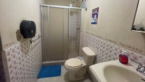 Baño pequeño con inodoro, ducha y lavamanos.