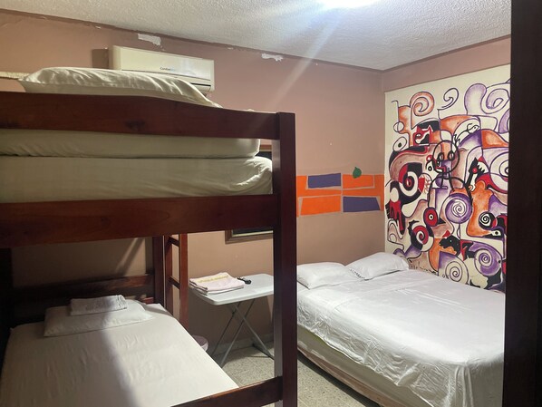 Une chambre avec des lits superposés, un bureau et une fresque murale abstraite aux couleurs vives.