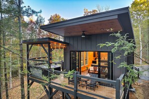 Een moderne cabin met terras, grote ramen en een gezellig interieur.