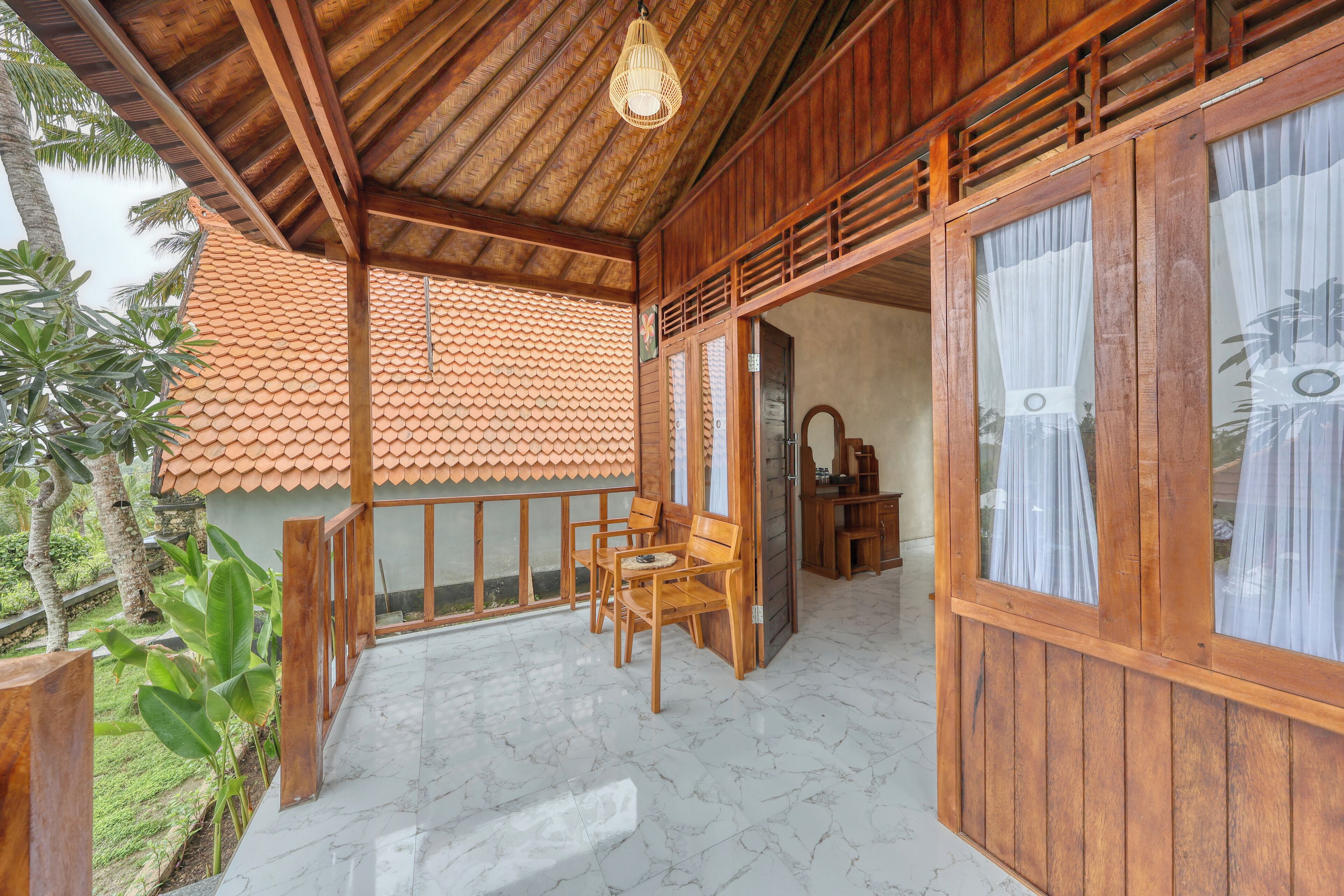 A wooden porch with a tiled roof, wooden furniture, and a view of the surrounding greenery.