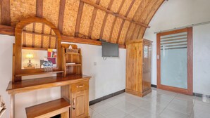 Una habitación con un escritorio de madera, un televisor montado en la pared y un armario con puerta de cristal.