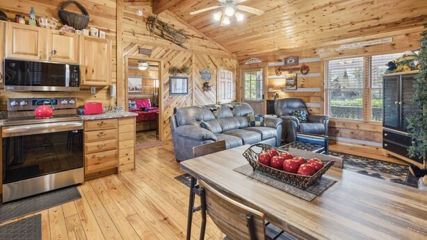 A cozy cabin interior with a kitchen, dining area, and seating space. - Lovey Bear - A Cozy Dog-Friendly Cabin with Hot Tub, Fireplace – Across from Soaky Mountain (Sevierville)
