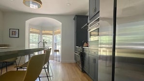Una cocina moderna con una isla central, electrodomésticos de acero inoxidable y ventanas amplias.