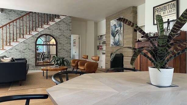 Amplia sala de estar con escalera, chimenea y mesa de comedor.