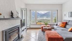 Una sala de estar moderna con chimenea, un sofá y vistas a montañas.