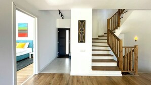 A spacious hallway with a wooden staircase and a bed with colorful pillows. - Nicme Villa Bran: Game Room and Barbecue (Bran)