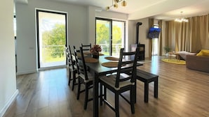 A spacious living area with a dining table, chairs, a sofa, and a TV. - Nicme Villa Bran: Game Room and Barbecue (Bran)