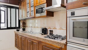 Una cucina con mobili in legno, un forno a microonde, un fornello e una lavastoviglie.