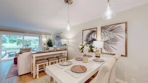 Un espace repas avec une table blanche dressée pour quatre personnes, entourée de sièges rembourrés.