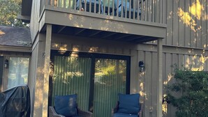 Un espace extérieur aménagé, abrité et doté de mobilier en osier, offrant une vue sur le jardin arrière.