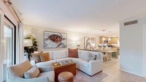 Un salon moderne avec un canapé d’angle, une table basse et un coin repas à l’arrière-plan.