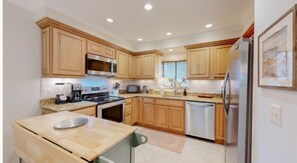 A modern kitchen with wooden cabinets, stainless steel appliances, and a granite countertop.