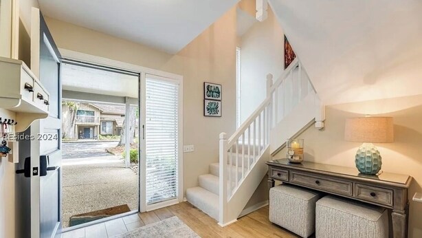 Un intérieur moderne avec un escalier, une porte donnant sur l’extérieur et un petit bureau avec une lampe.