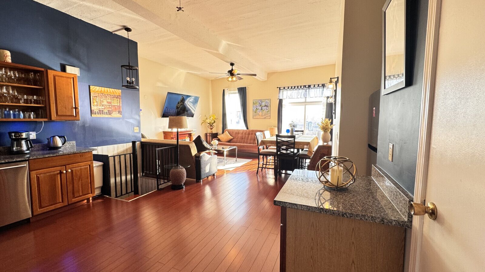 A spacious living area with a kitchen, dining area, and a large window providing natural light.