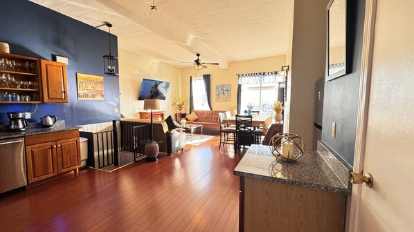 A spacious living area with a kitchen, dining area, and a large window providing natural light.