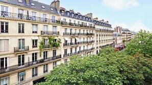 A row of multi-story buildings with balconies, likely residential apartments, with a clear sky and some greenery in the foreground. - Quiet Studio for 2 People - Le Marais (Paris)