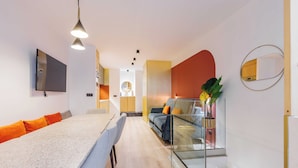 A modern kitchen with a flat-screen TV, a dining area with a long table and chairs, and a glass railing overlooking the space. - Charming Duplex - 2br/6p - In the Heart of Odeon (Paris)