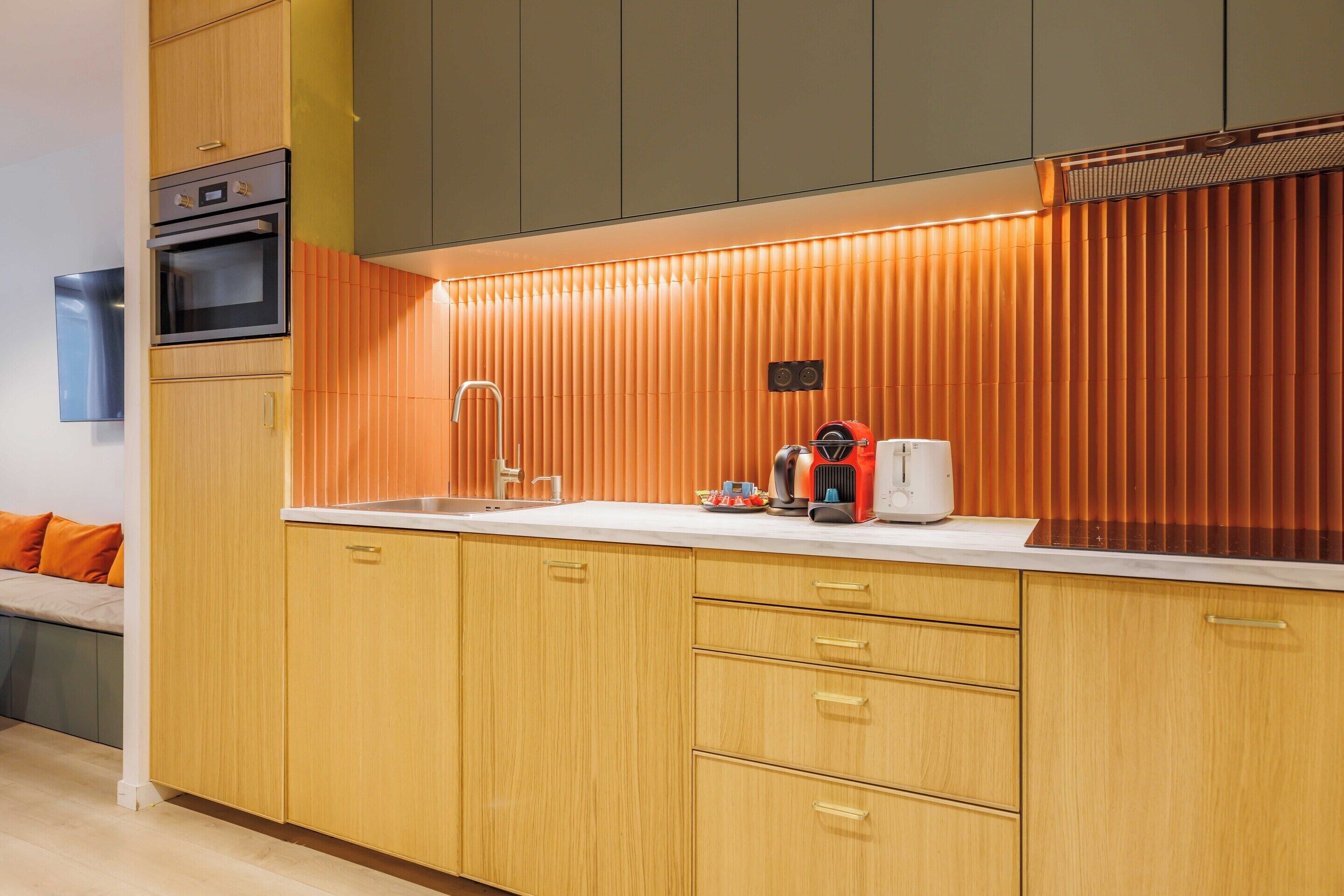 Una cocina moderna con armarios de madera, horno de acero inoxidable, un lavamanos y una campana extractora integrada.