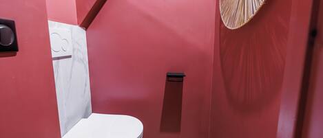 A bathroom with a white toilet, a shower, and a wall-mounted towel rack.