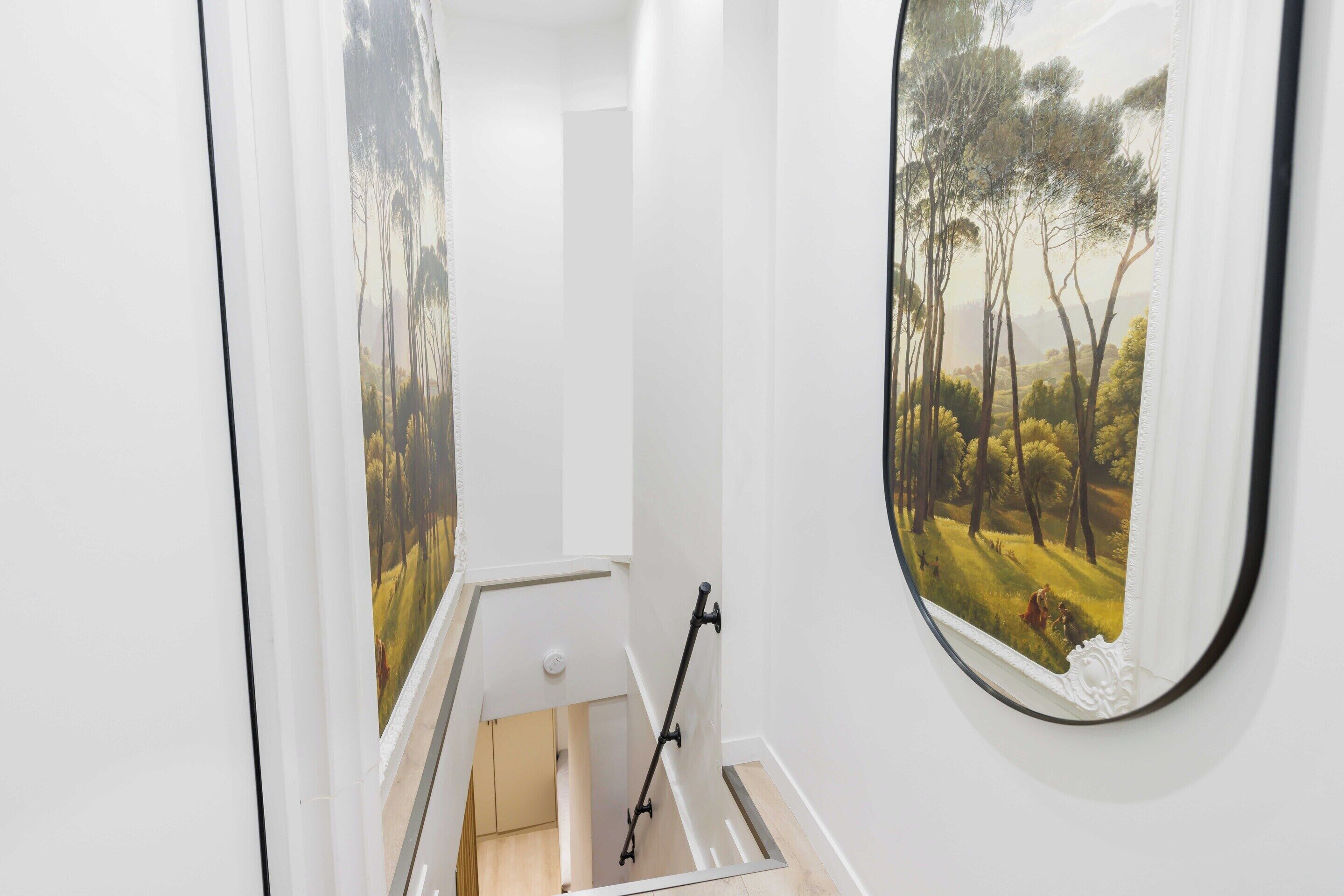 A staircase with a painting of a forest scene on the walls.