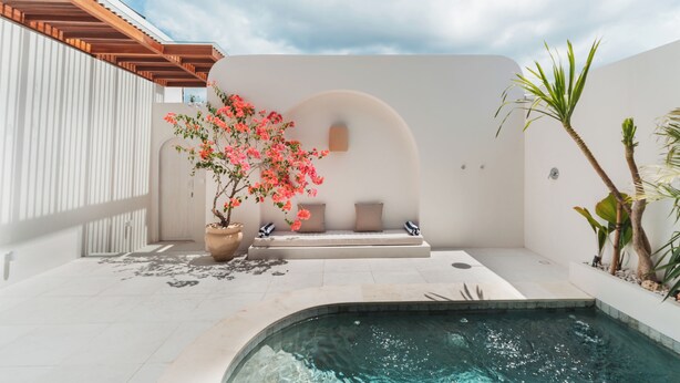 A modern outdoor pool area with a seating bench, a potted plant, and a clear sky. - Villa Sari 1 by Alfred in Bali (Pecatu)