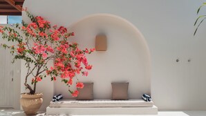 A white wall with a large potted plant and a bench with cushions. - Villa Sari 1 by Alfred in Bali (Pecatu)
