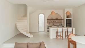 A modern kitchen with a central island, white cabinetry, and a built-in oven. - Villa Sari 1 by Alfred in Bali (Pecatu)