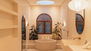 A modern bathroom with a freestanding bathtub, a large mirror, and a vanity with a sink. - Villa Sari 1 by Alfred in Bali (Pecatu)