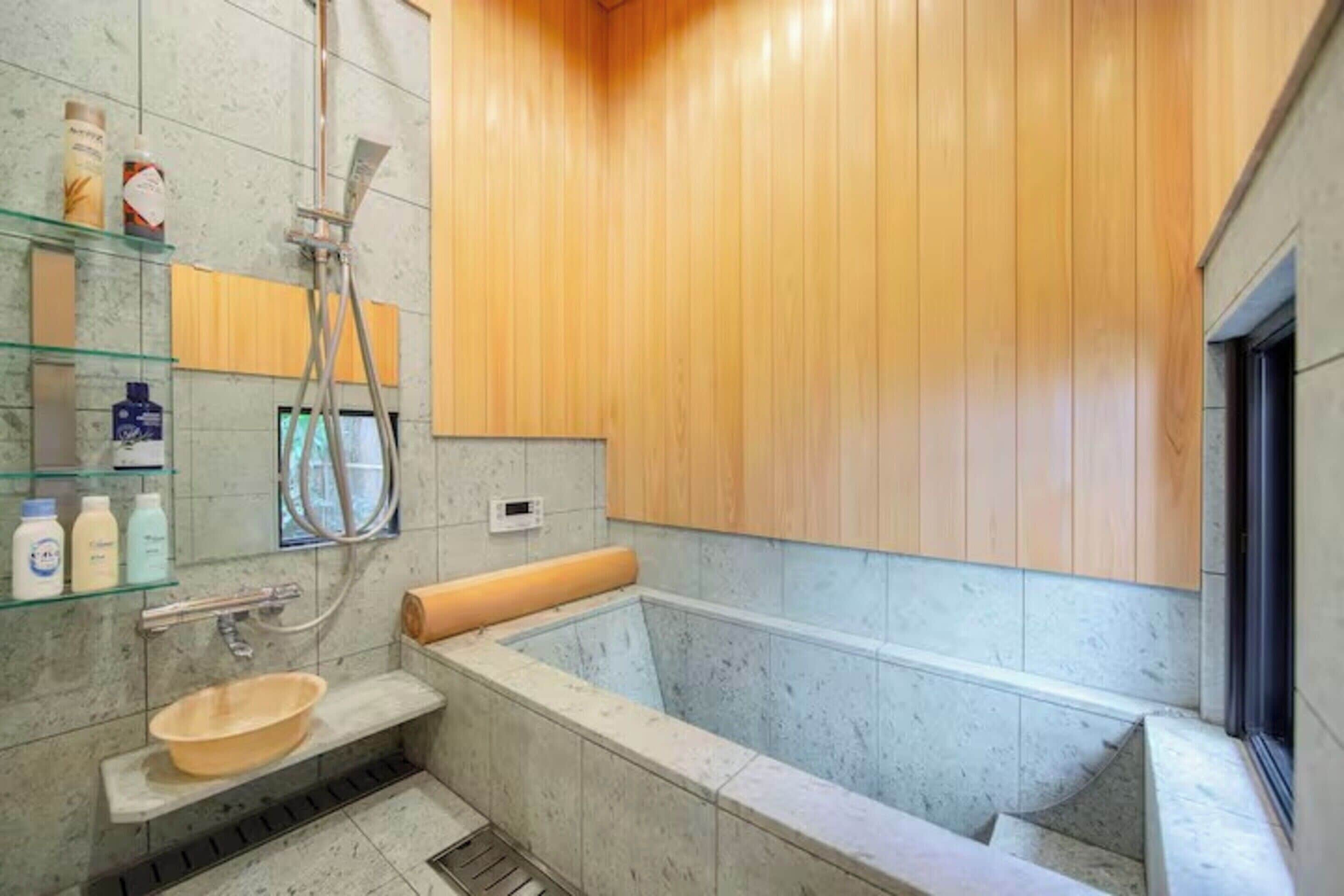 Un baño moderno con una bañera independiente, un estante de vidrio con artículos de aseo y paneles de madera en las paredes.