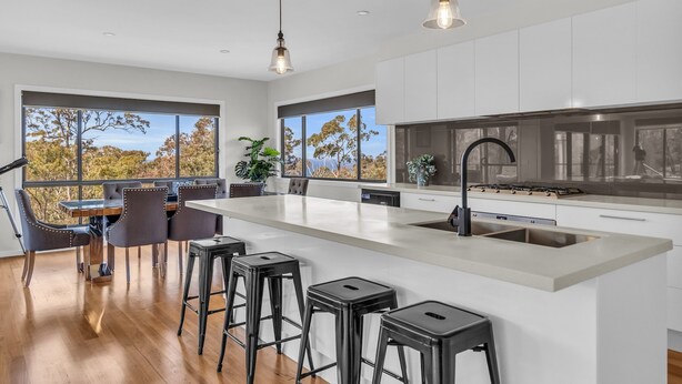 Una cocina moderna con una isla grande, taburetes de bar e iluminación colgante.