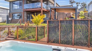 Una casa moderna de dos pisos con un balcón, una piscina y una valla decorativa.