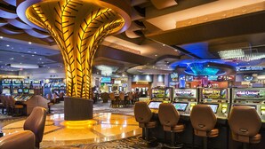 A casino interior with slot machines, a large illuminated pillar, and comfortable seating areas.