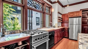 A modern kitchen with a large window, stainless steel appliances, and wooden cabinetry.