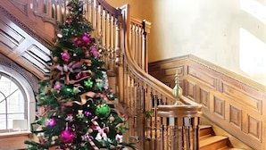 A grand staircase with a decorative railing and a Christmas tree adorned with ornaments and ribbons.