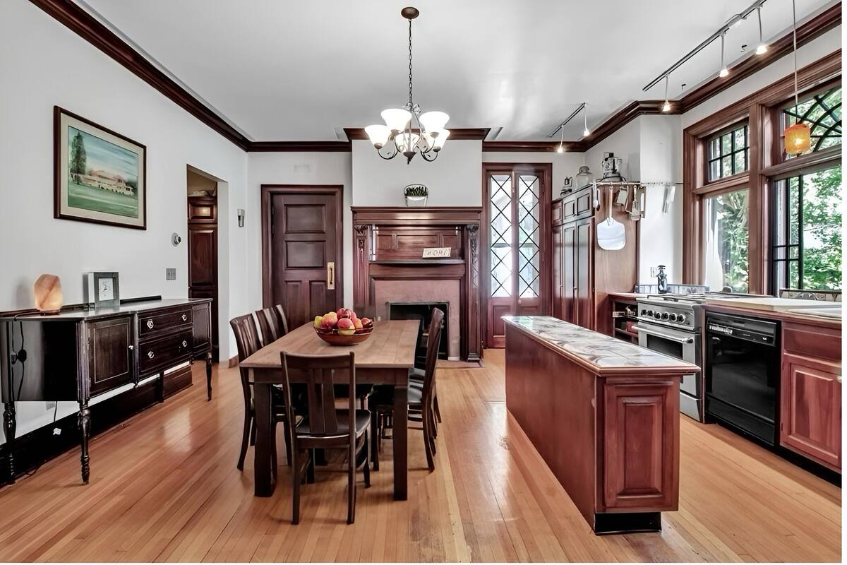 A spacious kitchen with wooden cabinetry, a central island, and a dining area with a table and chairs.