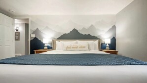Ein Schlafzimmer mit einem Bett, zwei Nachttischen und einer Wandmalerei von Bergen.