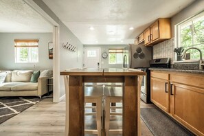 Une cuisine moderne avec des meubles en bois, un réfrigérateur en acier inoxydable et une grande fenêtre qui laisse entrer la lumière naturelle.