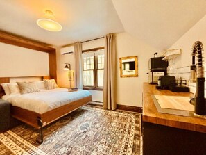 A bedroom with a bed, a desk, a chair, a mirror, and a window. - Estello Suites et Spa (Frontenac)