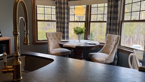 A kitchen with a large island, two chairs, a dining table, and a pendant light. - Estello Suites et Spa (Frontenac)