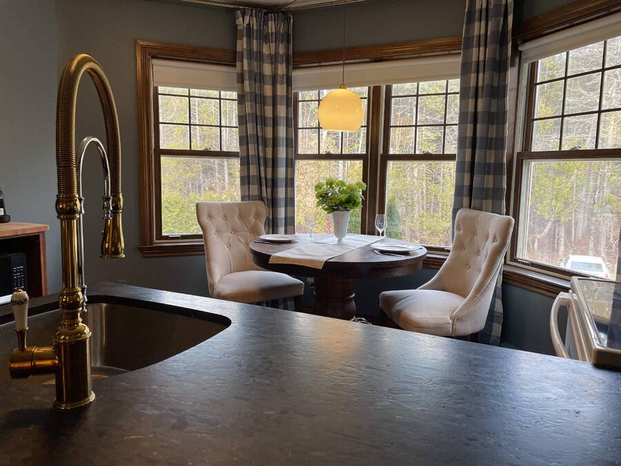 A kitchen with a large island, two chairs, a dining table, and a pendant light.