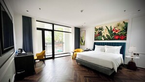 Una camera d'albergo con un letto grande, una scrivania, una sedia, un tavolino e un quadro appeso al muro.