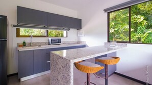 Een moderne keuken met donkere kastjes, een granieten aanrechtblad en een groot raam met uitzicht op groen.
