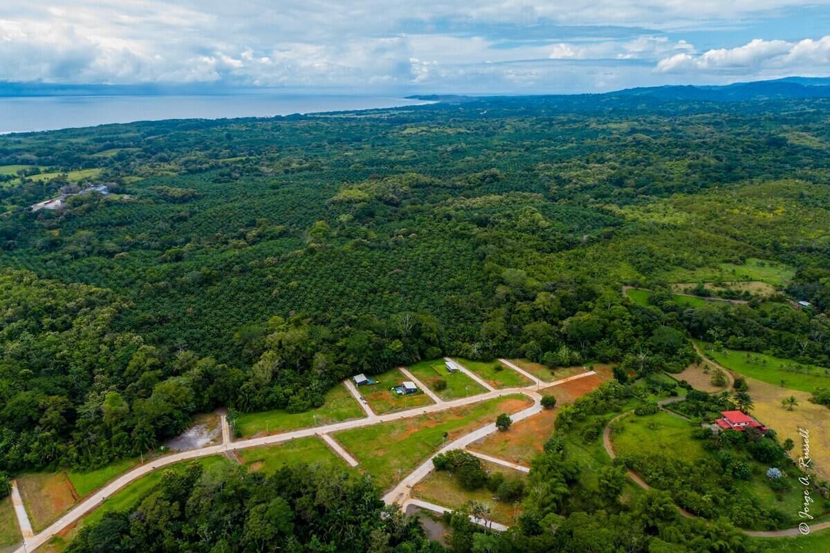 An aerial view of a rural area with scattered buildings, roads, and a large body of water in the background.