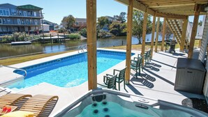 Uma área de piscina com hidromassagem, espreguiçadeiras e vista para um lago.
