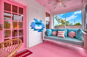 A pink-themed room with a large window, a wall mural, and a sofa with cushions. - 4 BDR Heated Pool, Professionally Designed Vacation Rental Across from Beach (Tybee Island)