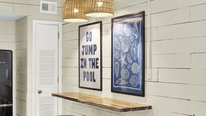 Een kamer met een witte deur, een lijst met daarop de tekst 'GO JUMP IN THE POOL' en een muur met een kunstwerk in zeestijl.